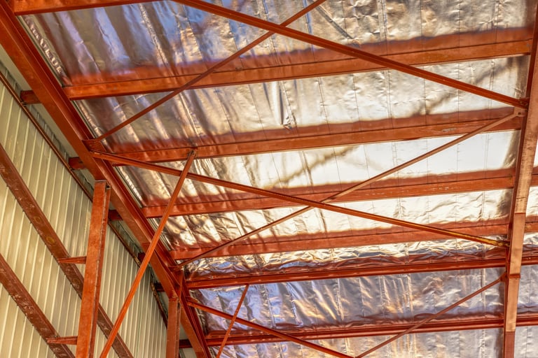 Metal building roof insulation with spray foam