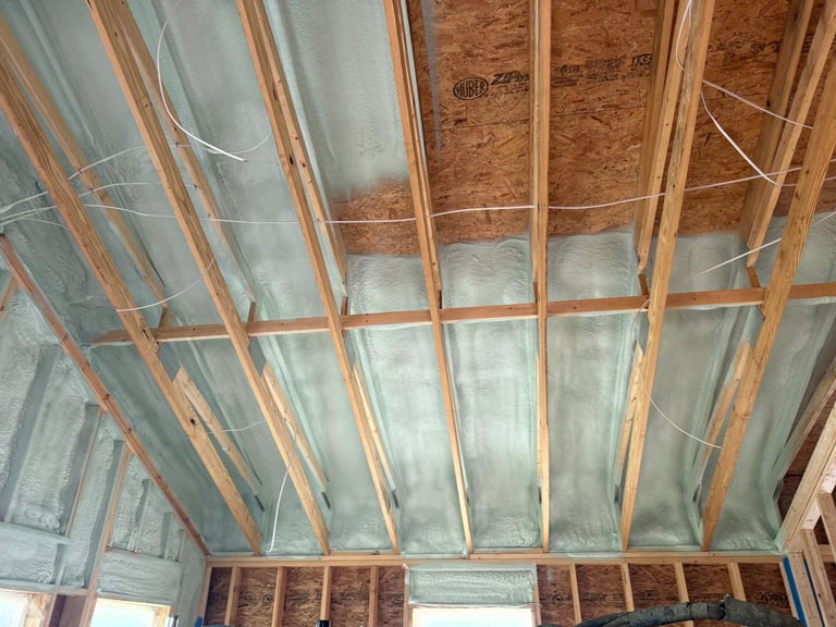 Interior view of unfinished ceiling with wooden framing, insulation, and drywall installation in progress