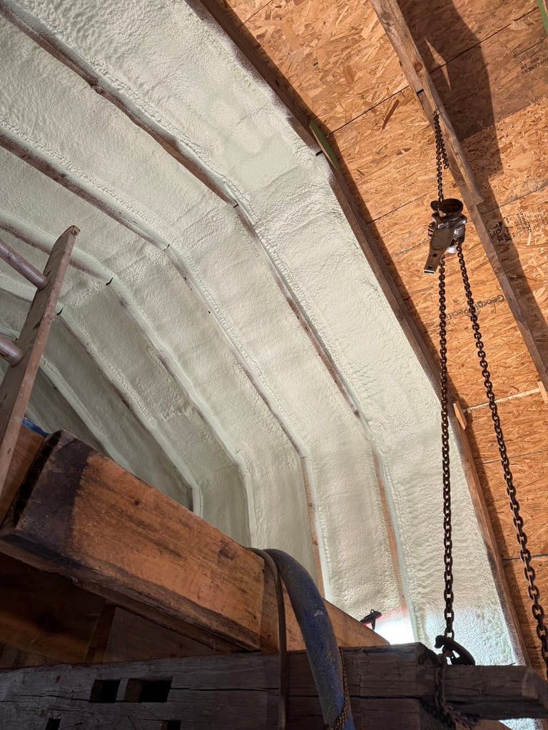 Interior of greenhouse with white plastic sheeting covering arched wooden frame and chain pulley system